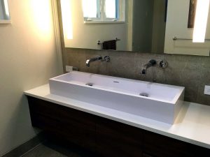 A newly remodeled bathroom with a white trough-style sink