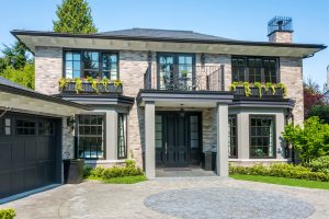 A newly remodeled home with gray brick and black windows, doors, and garage