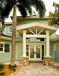 Exterior of large, beach-style home with green siding 