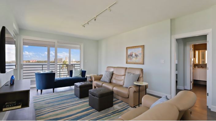 Condominium living room with striped throw rug, tan couch, and balcony 