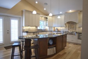 Updated kitchen with white cabinets, overhead lighting, and an island with brown cabinetry 