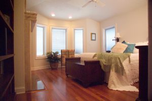 Bedroom with hardwood floors, large bed, and multiple windows 