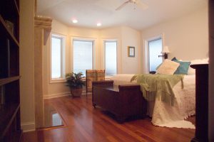 Bedroom with a bed, wood floors, and four windows