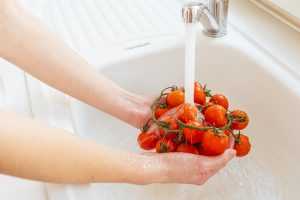 Person washing tomatoes in the sink